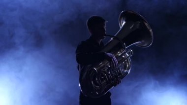 Müzisyen bir tuba oynarken dumanlı bir stüdyoda siluet