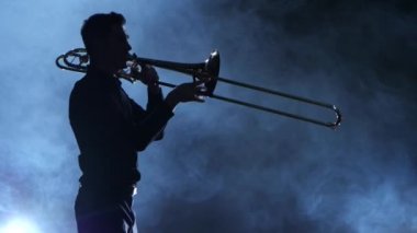 Siluet profesyonel müzisyen adam trompet üzerinde oynama. Dumanlı izole stüdyo