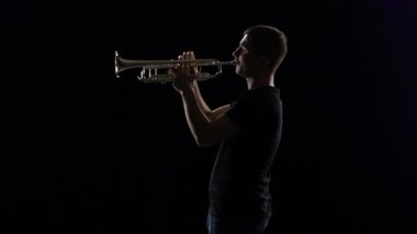 Trompetçi adam Nefesli/Üflemeli Saz melodi çalar. Siyah stüdyo arka plan