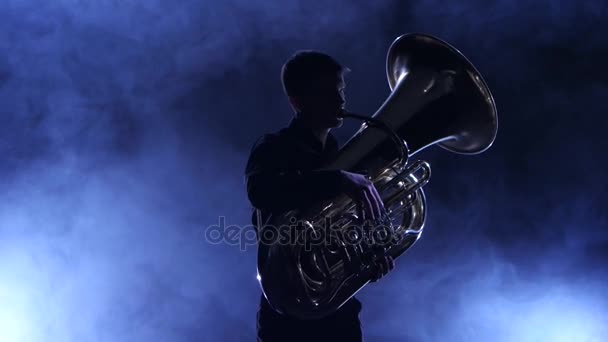 Músico em um estúdio fumegante tocando em uma tuba, silhueta — Vídeo de Stock