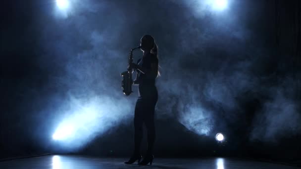 Instrumentalist woman plays on wind instrument saxophone melody. Smoky studio — Stock Video