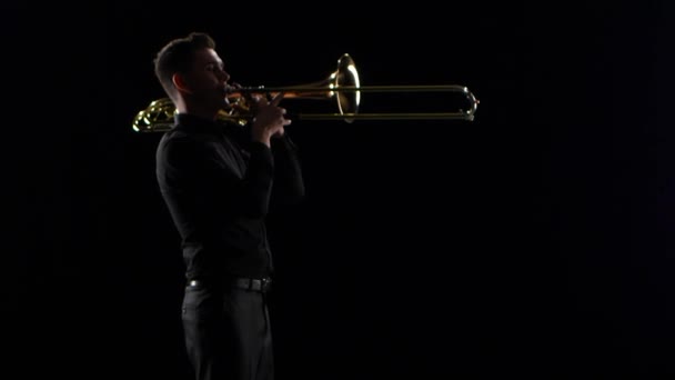 Trompettist speelt op blaasinstrument rustige melodie. Zwarte studio achtergrond — Stockvideo