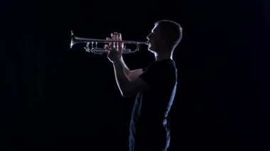 Adam trompetçi motif Nefesli/Üflemeli Saz esiyor. Siyah stüdyo