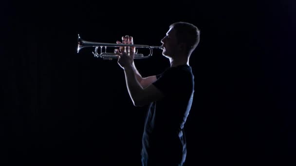 Man trumpeter blows the motif in wind instrument. Black studio — Stock Video