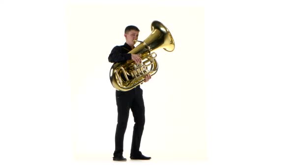 El hombre toca en la tuba melodía lenta en fondo blanco — Vídeo de stock