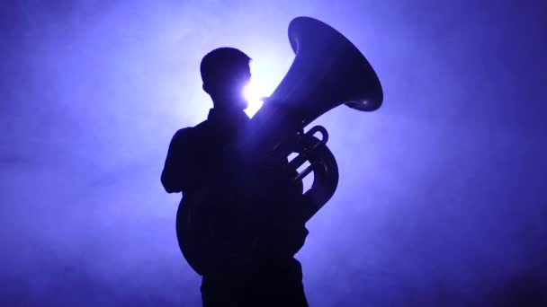 Muzikant in silhouet spelen in tuba, rokerige studio. Slow motion — Stockvideo