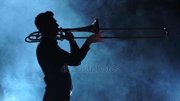 Siluet müzisyen adam trombonunu oynuyor. Dumanlı stüdyo, ağır çekim — Stok video