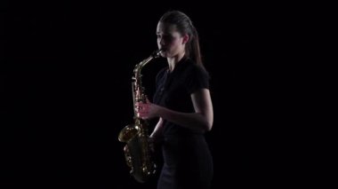 Esmer saksafon yavaş hareket üzerinde çalış. Siyah stüdyo arka plan