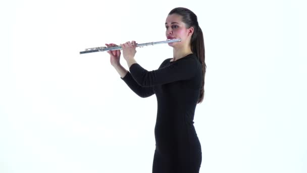 Девушка-музыкант играет на флейте стоя боком в замедленной съемке — стоковое видео
