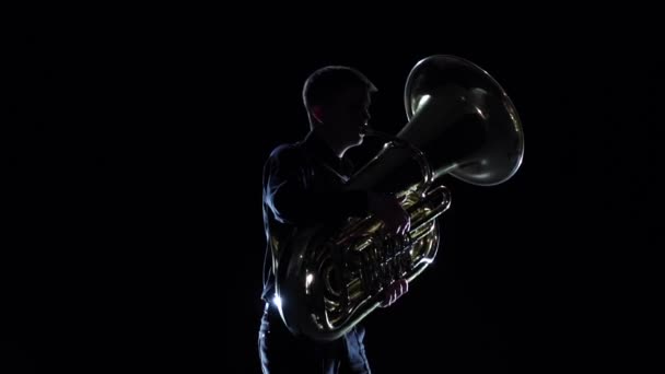 Mann spielt im schwarzen Studio auf Tuba-Melodie. Zeitlupe — Stockvideo