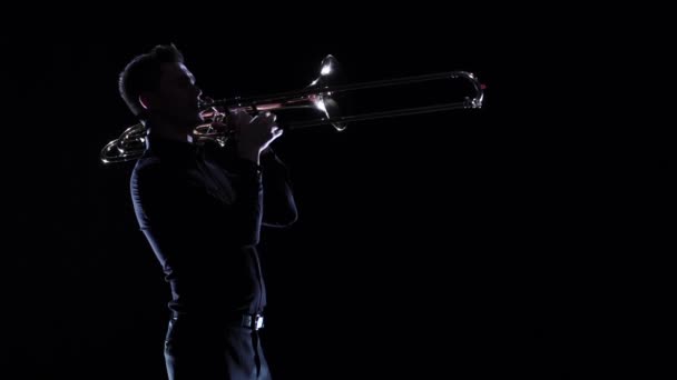 Трубач играет на мелодии духового инструмента в темноте. Медленное движение — стоковое видео