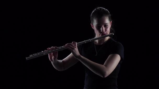 Женщина играет на флейте классические мелодии, черный фон. Медленное движение — стоковое видео