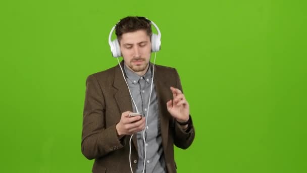 Guy listens to music through headphones, dances and sings. Green screen — Stock Video