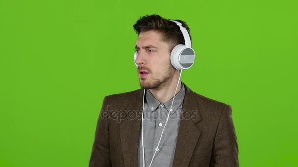 Junge Geschäftsmann hört leise Musik über Kopfhörer. Green Screen. Zeitlupe — Stockvideo