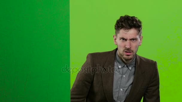 El hombre de negocios mira desde detrás de un tablero verde y grita mucho. Pantalla verde. Movimiento lento — Vídeo de stock