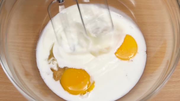 Ingrediënten voor omelet in glazen kom zweep mixer. Slow motion — Stockvideo