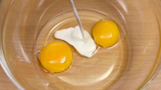 Melk wordt gegoten in de plaat met eieren in slow motion — Stockvideo
