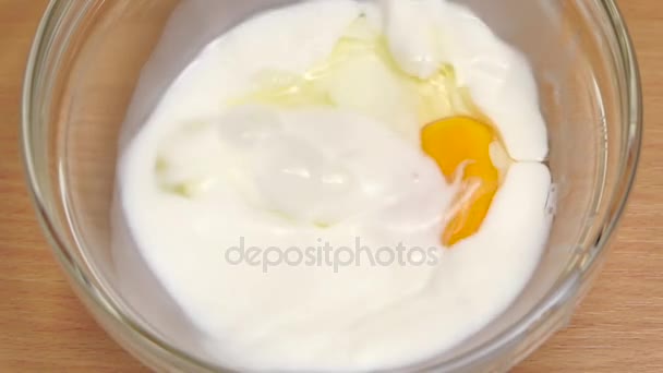 Одно свежее куриное яйцо разбивается в тарелке с молоком — стоковое видео