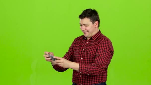 Man takes pictures on the phone, he is happy and cheerful. Green screen — Stock Video