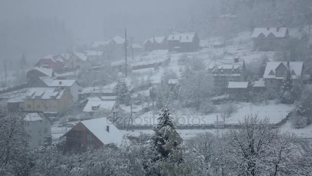Χιόνι πέφτει στο χωριό στο πόδι κατάφυτο λόφο. Αργή κίνηση — Αρχείο Βίντεο
