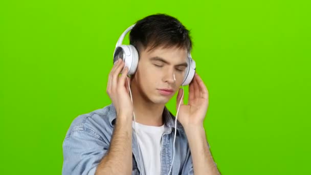 Facet słucha muzyki w słuchawkach i dostosowuje się do pozytywnych. Zielony ekran — Wideo stockowe