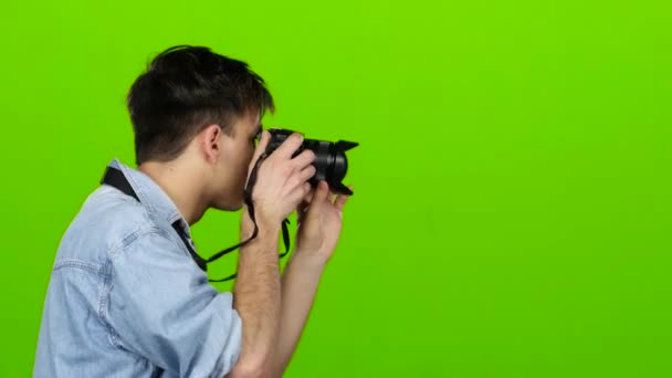 Guy está segurando uma câmera e fazendo belas fotos de outros. Tela verde — Vídeo de Stock