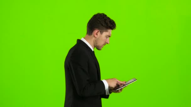 Guy looks at the photo on the phone and finds a list of pictures,. Green screen. Side view — Stock Video