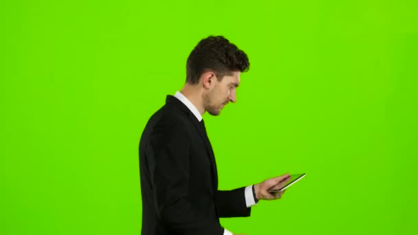 El hombre de negocios camina, pulsa un cuaderno, y hace una selfie. Pantalla verde. Vista lateral — Vídeos de Stock