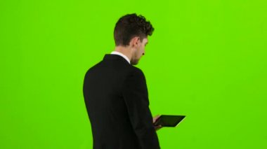 İşadamı yürür, bir not defteri başparmak ve bir selfie yapar. Yeşil ekran. Arkadan Görünüm
