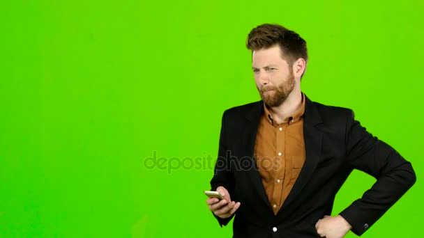 Чоловік дивиться на телефон на фото і розважається. Зелений екран — стокове відео