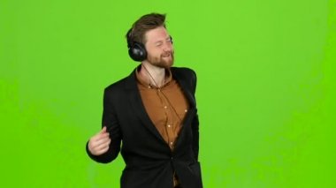 Adam kulaklık müzik, dans etmek dinliyor ve bir şarkı söyler. Yeşil ekran. Ağır çekim