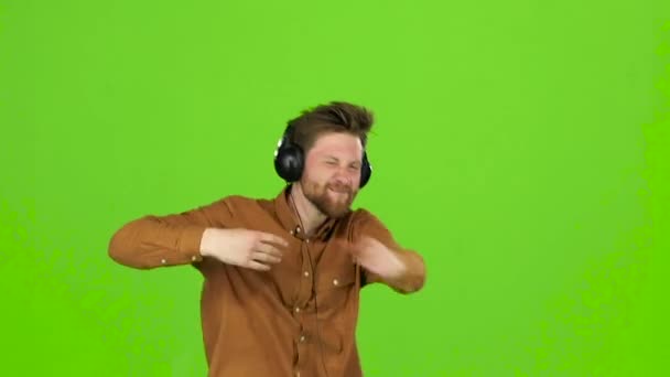 Der Typ mit den Kopfhörern tanzt und wirbelt herum und hat Spaß. Green Screen — Stockvideo