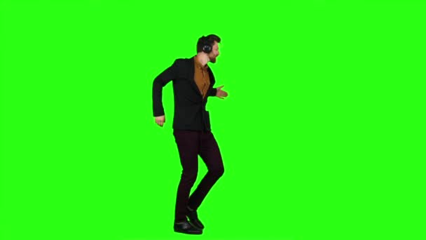 Homem de fones de ouvido ouve música, dança e canta uma música. Tela verde. Movimento lento — Vídeo de Stock