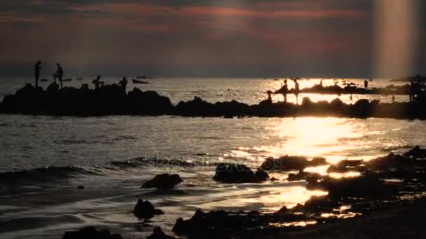 La gente del atardecer se baña, en la playa del mar nadan los barcos, las olas salpican alrededor de la orilla — Vídeo de stock