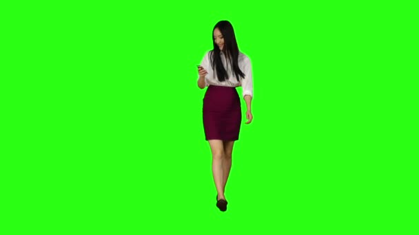 Chica de apariencia asiática camina por la calle, el teléfono mira fotos interesantes. Pantalla verde. Movimiento lento — Vídeos de Stock