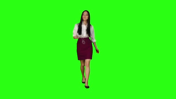 Aziatische meisje gaat werken en luistert naar muziek in de koptelefoon. Groen scherm. Slow motion — Stockvideo