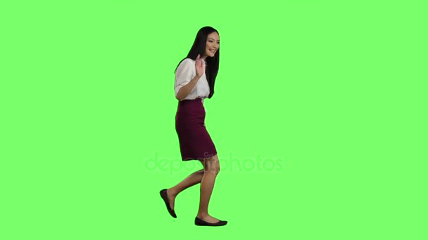 Chica de apariencia asiática va a trabajar y agita su mano. Pantalla verde. Vista lateral. Movimiento lento — Vídeo de stock