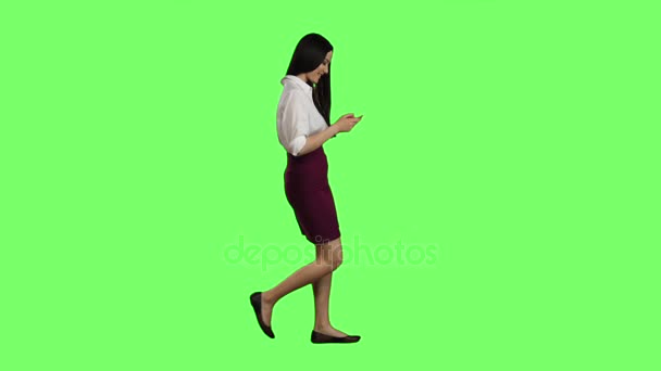 Chica de apariencia asiática camina por la calle, el teléfono mira fotos interesantes. Pantalla verde.cc — Vídeo de stock