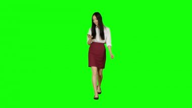 Kız yürüyor ve bir telefon tutar ve fotoğraflara görünüyor. Yeşil ekran