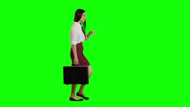 Азиатка смотрит на дорогу, держа в руках портфель. Зеленый экран — стоковое видео