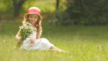 Çocuk bir buket çiçekler onun elinde tutan, o onları kokuyor ve gülümsüyor