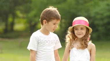 Küçük çocuk kız yanağından öpüyor, o utanıyor ve gülümsüyor. Ağır çekim