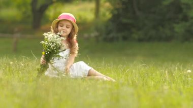 Çocuk bir buket çiçekler onun elinde tutan, onları kokuyor ve gülümsüyor. Ağır çekim