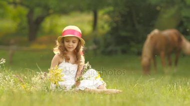 Bebek bir takas oturur, yırtık kır çiçekleri üzerinde döner ve onlardan bir buket yapar. Ağır çekim