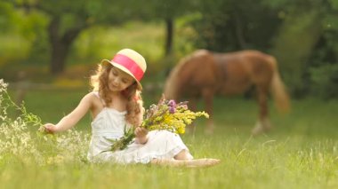 Çocuk bir takas oturur, yırtık kır çiçekleri üzerinde döner ve onlardan bir buket yapar. Ağır çekim