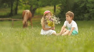 Küçük çocuk bir kız için bir buket çiçegi verir. Ağır çekim