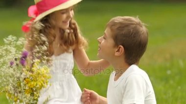Küçük çocuk bir kız için bir buket çiçegi verir. Ağır çekim