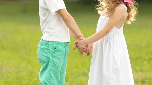 Children hold hands, the girl is embarrassed and smiles. Slow motion — Stock Video