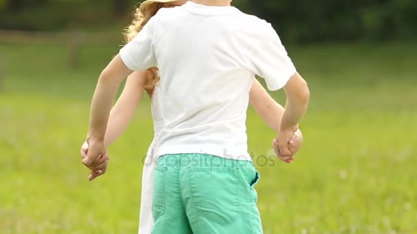 Die Kinder halten sich an den Händen und beginnen im Sommerpark gemeinsam zu kreisen. Zeitlupe — Stockvideo