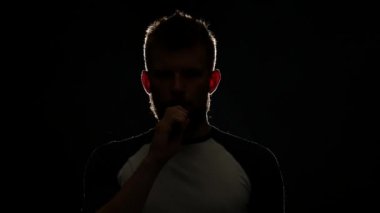 Adam elektronik sigara elinde tutuyor, soluk ve çok fazla duman exhales. Siyah arka plan